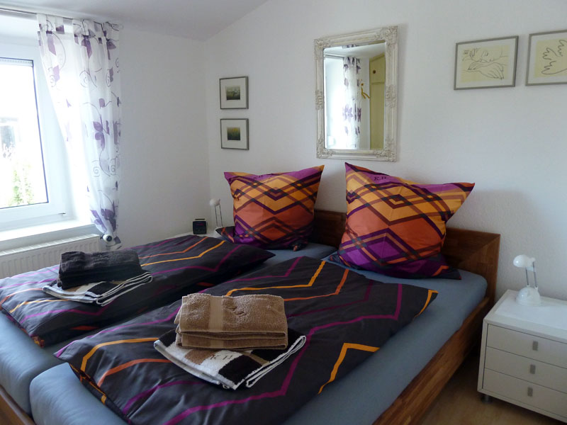 Elternschlafzimmer mit Bettwäsche und Handtüchern im Ferienhaus Kolks Huus in Neuharlingersiel an der Nordsee